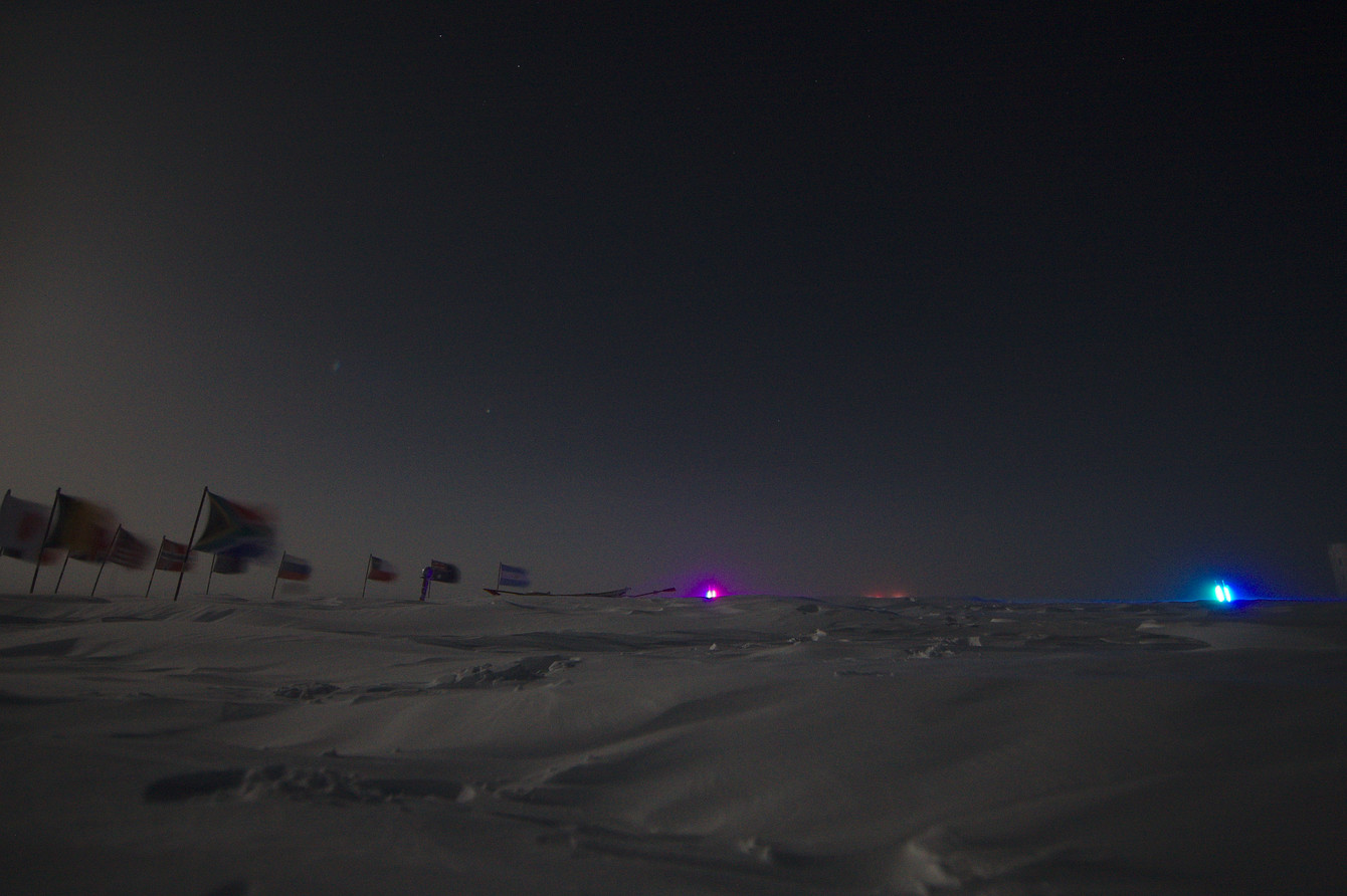 Discipline 9 - Group sled pull to the ceremonial pole. The finish line is marked by lights. The red lights of some participants can be seen on the horizon.