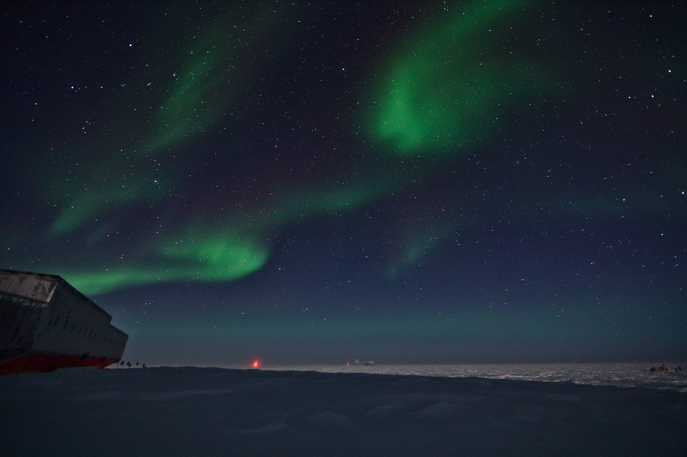 The frozen landscape behind the station illuminated by moon light and auroras