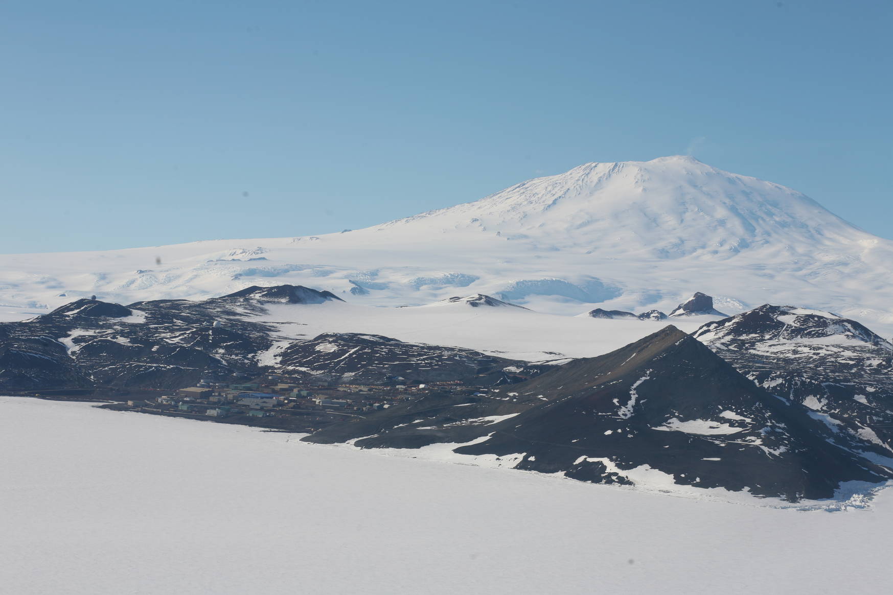 A first view of the McMurdo base: the white mountain in the background is the active volcano Erebus. The hill to the front right is the 'Observation hill'.
